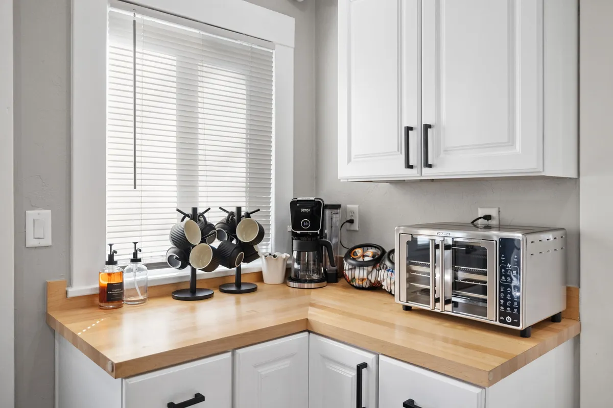 A cozy corner dedicated to a coffee-making setup, including a coffee maker, toaster oven, and a charming mug holder. The ambiance is intimate, perfect for brewing morning coffee or enjoying a quiet breakfast.