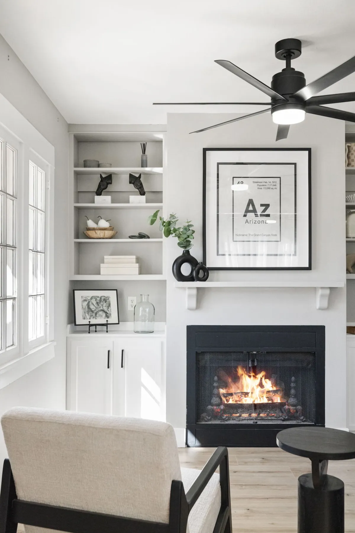 A well-appointed sitting area featuring an armchair beside the fireplace, with elegant artwork and shelf décor contributing to the sense of refined heritage. The overall mood is both stately and contemporary, with abundant natural light accentuating the details.