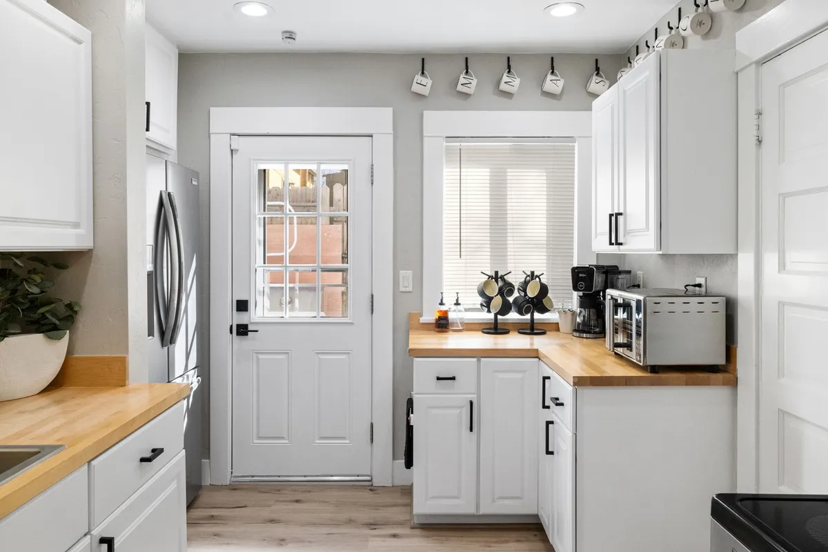 A welcoming kitchen space featuring a spacious counter, modern kitchen appliances, a window bringing in natural light, and a doorway that hints at the kitchen's centrality within the home. The area is both functional and sociable, ideal for meal preparation and casual conversation.