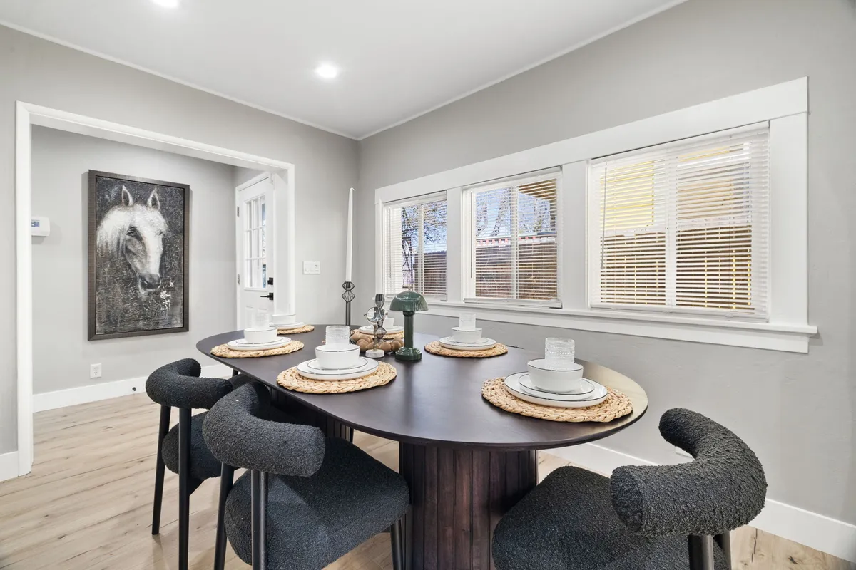 A warm and welcoming dining area with a beautifully set table, decorative horse artwork, and a large window letting in natural light. The space is styled for both intimate family meals and larger social gatherings.