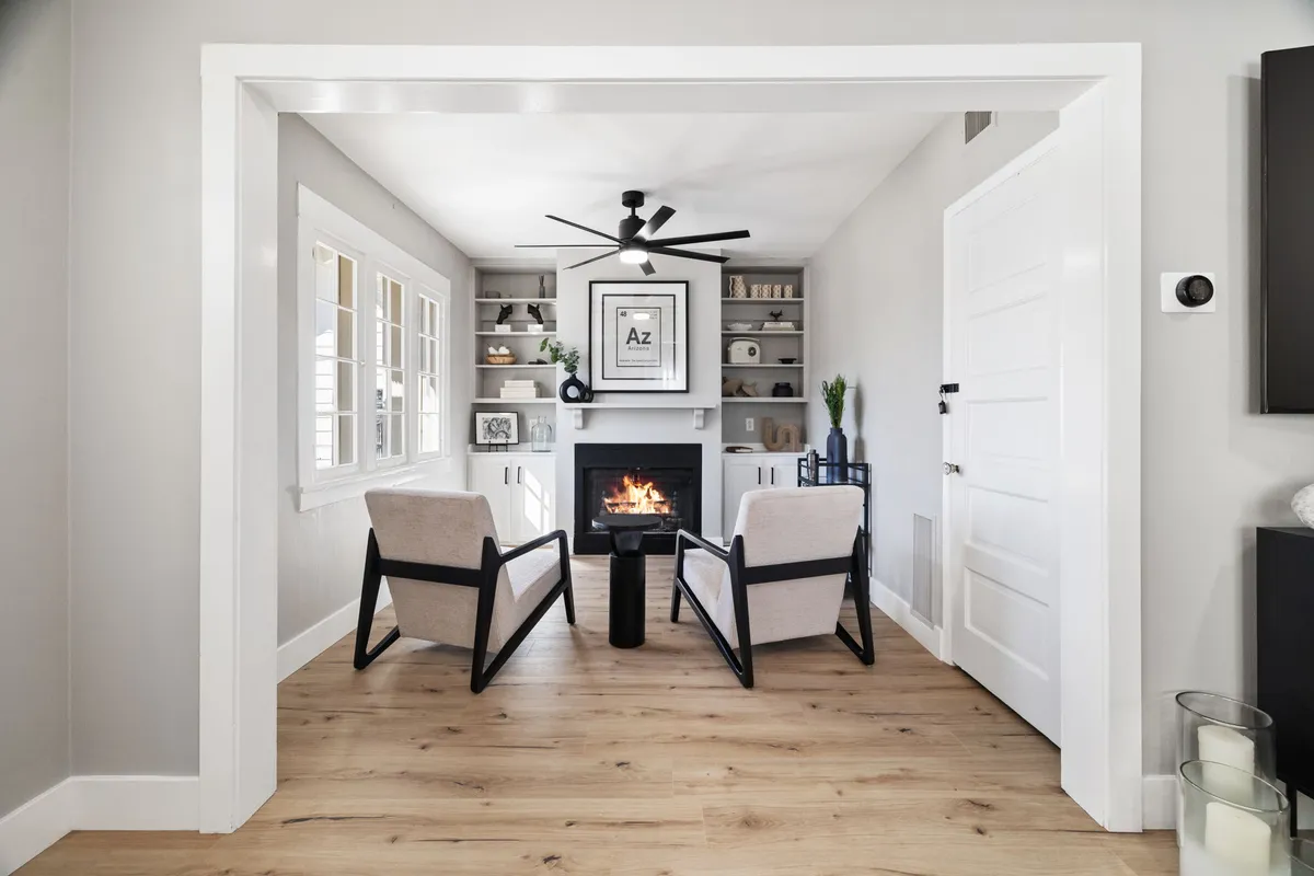 A close-up view of the sitting room's fireplace, flanked by two armchairs and shelves. The intimate setup suggests a place for reading, relaxation, and warm conversations, with period-style woodwork and thoughtful staging.