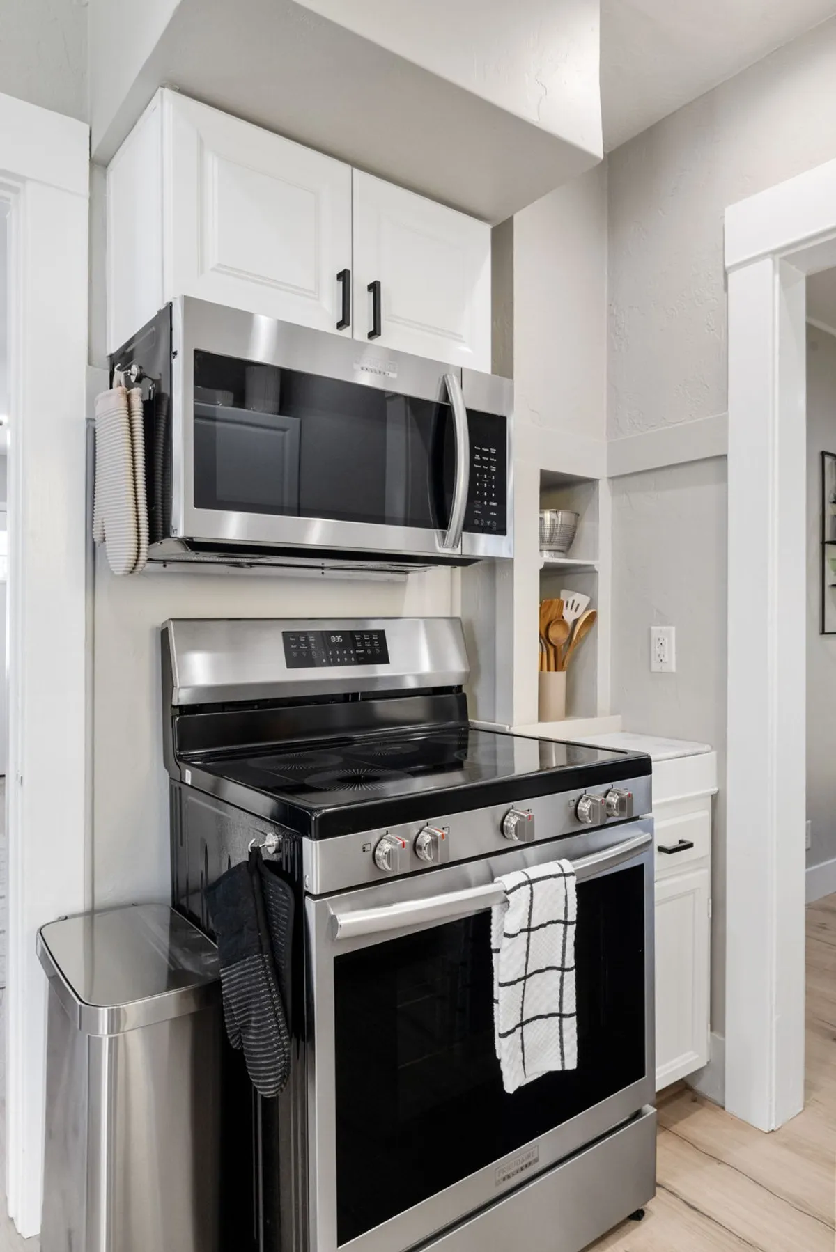 A well-organized kitchen with a modern stainless steel stove, microwave, visible utensils, and a clean countertop. The scene evokes warmth and hospitality, perfect for hosting holiday dinners, baking with kids, or preparing meals for a group.
